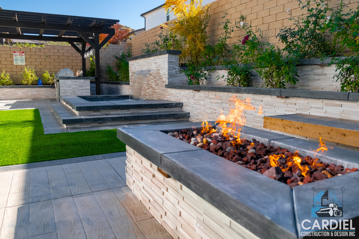 Transformed backyard with a custom outdoor kitchen, pergola, spa, firepit, lush plants, and pristine turf—a perfect oasis for outdoor living and entertaining.