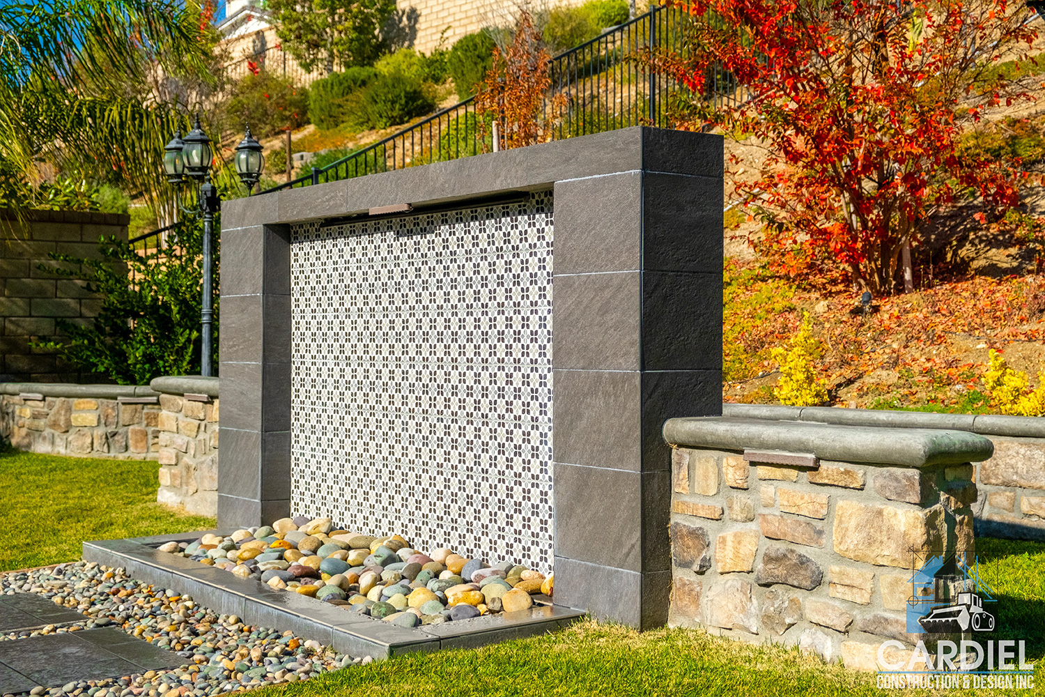 Outdoor water feature with cascading design, complemented by natural stones and lush greenery.